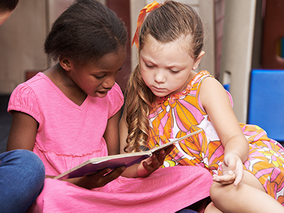 Two young girls reading a book